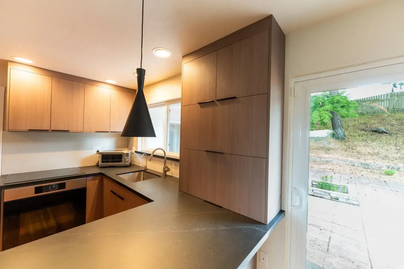 Walnut kitchen with black counters and a pendant