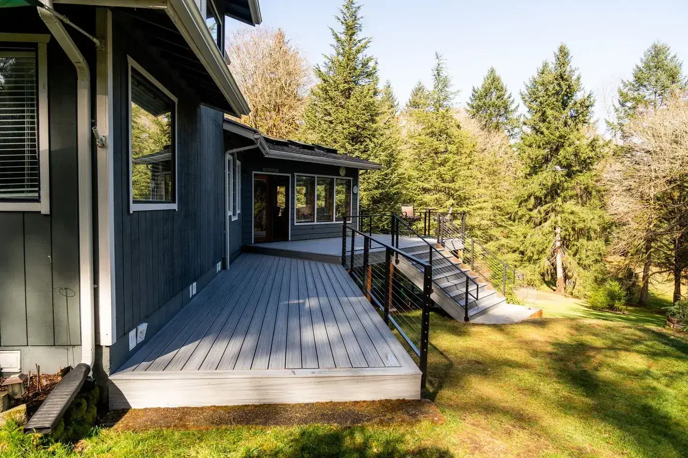 Composite deck with cable railing wrapping a blue house