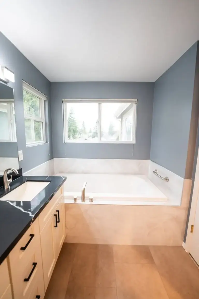 Soaking tub under the window, marble-look surround – Bathroom remodel in Renton, WA by NW Expert Builders