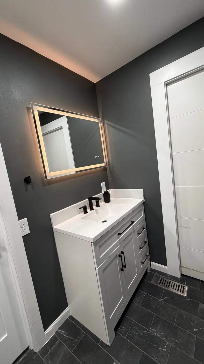 White vanity with LED mirror against charcoal walls
