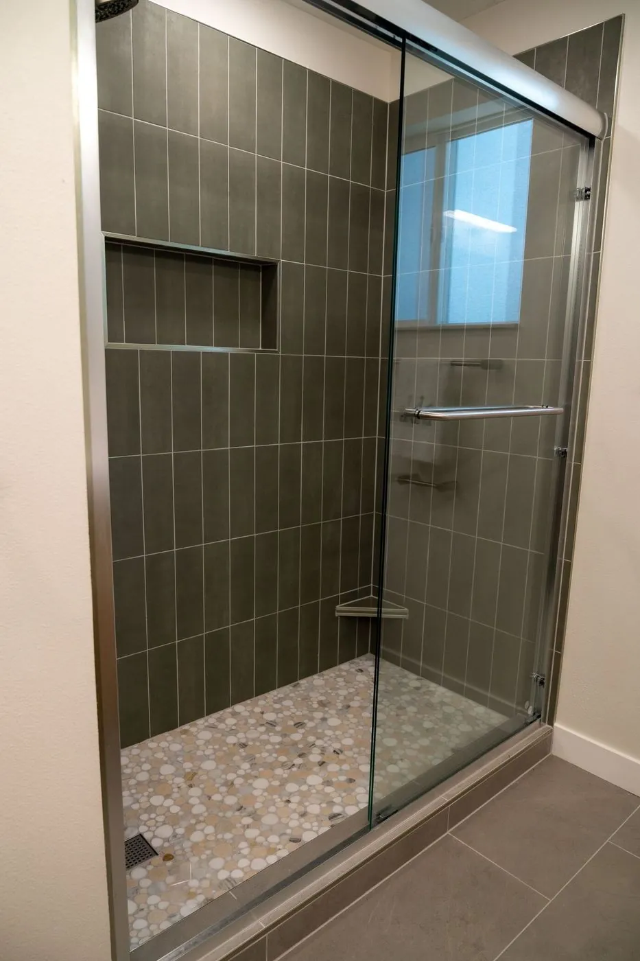 Sage green tiled shower with a glass door in Shoreline