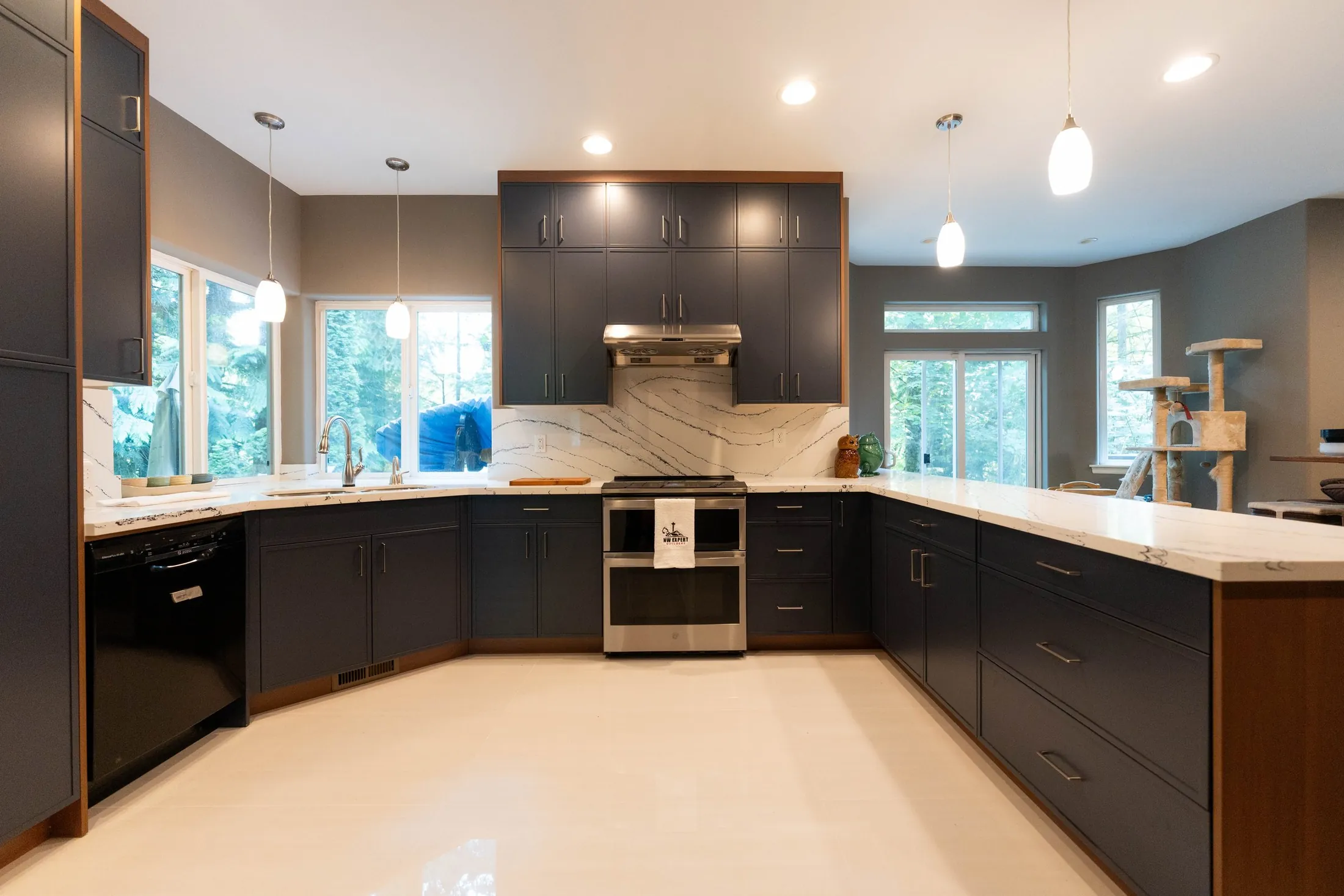 Finished kitchen with navy shaker cabinets, walnut accents and a veined quartz peninsula