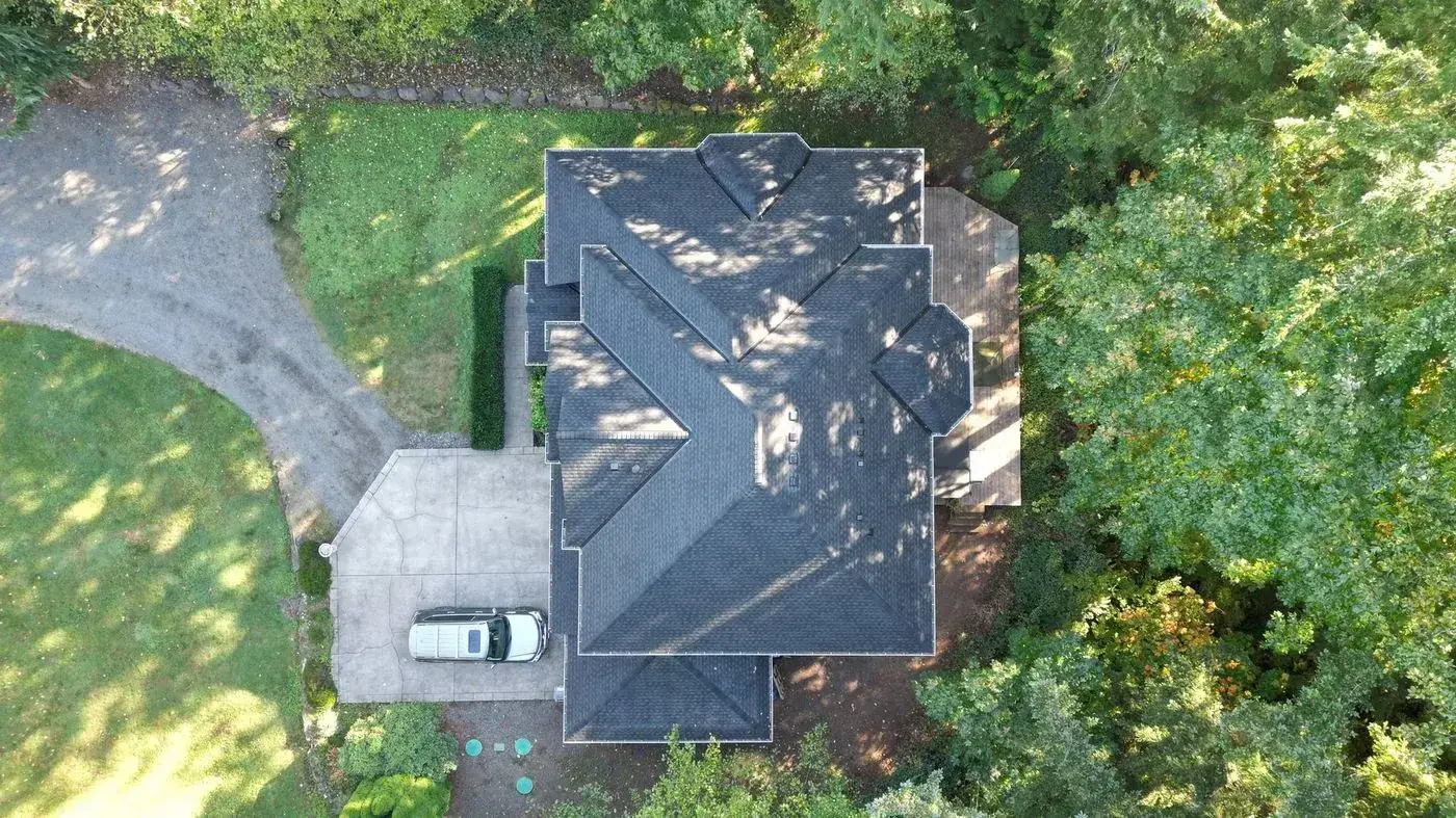Aerial: new charcoal shingle roof in a wooded lot